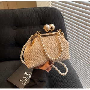 Detail of handmade woven straw bag featuring elegant pearl clasp and beaded straps