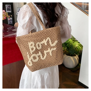 Dettaglio della borsa tote in paglia intrecciata a mano con ricamo bon jour