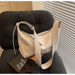 Detail of light grey crescent hobo bag with glossy leather texture on blue velvet
