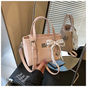 Detail der hellrosa Mini-Tasche mit Perlenanhänger und Spitzenschleife im Spiegelbild