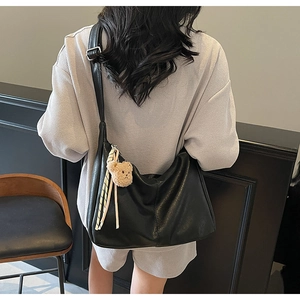 Detail of black PU leather tote bag with teddy bear charm and adjustable shoulder strap
