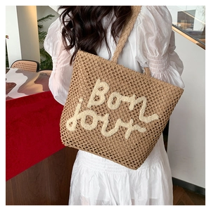 Dettaglio della borsa tote in paglia intrecciata a mano con ricamo Bonjour bianco