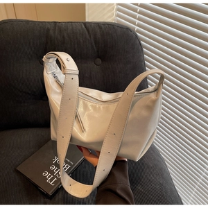 Close-up of creamy white crescent shoulder bag with wide adjustable eyelet strap