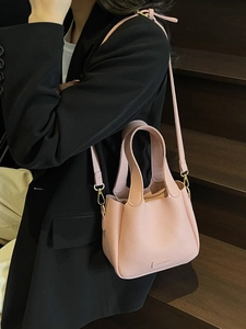 Chic pink bucket bag in lychee pattern leather with shoulder strap on a model