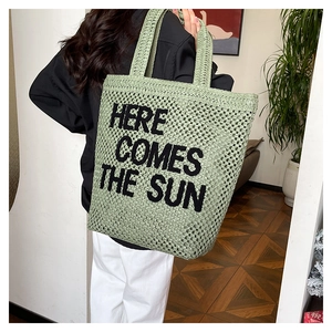Detail of light green woven tote bag with Here Comes The Sun embroidery and large capacity