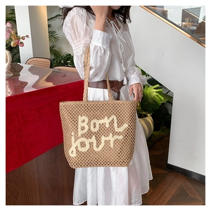 Dettaglio della borsa tote in paglia intrecciata a mano con ricamo bianco bon jour e capienza