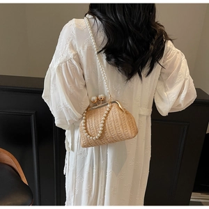 Detail of hand-woven beige straw bag with elegant pearl straps and gold clasp closure