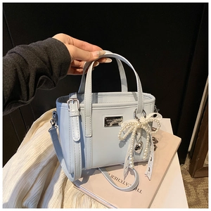 Nahaufnahme hellblaue Mini-Eimertasche mit Perlen-Schleife und Metall-Markenschild