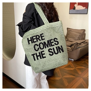Detail of green crochet beach tote with black Here Comes The Sun embroidered text