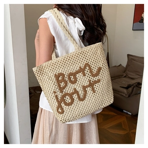 Dettaglio della borsa tote in paglia beige con ricamo Bon Jour marrone e spalline intrecciate