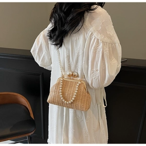 Detail of straw crossbody bag with pearl strap on model in elegant lace dress