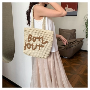 Dettaglio della borsa tote in paglia intrecciata con ricamo Bonjour marrone da spiaggia