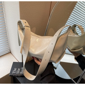 Detail of white glossy crescent bag with ruched texture and adjustable wide strap