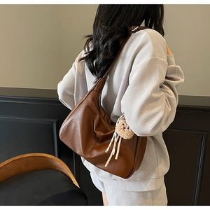 Brown matte leather hobo bag with teddy bear charm shown from a side perspective