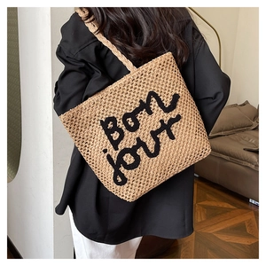 Borsa tote in paglia con ricamo Bon Jour sulla spalla in un ambiente minimalista