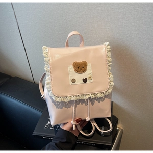 Detail of pink mini backpack with lace trim, plush bear patch and retro buttons