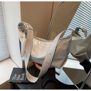Detail of silver metallic hobo bag with adjustable strap and polished zipper closure
