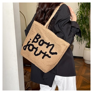 Dettaglio della borsa tote in paglia intrecciata con ricamo Bon jour nero e manici spessi