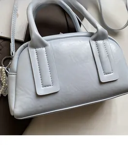 Detailed view of light blue leather boston bag with soft texture and pearl pendant