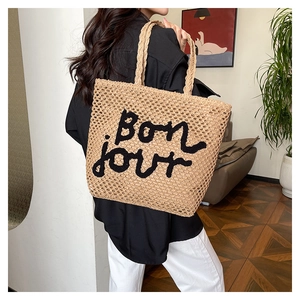 Dettaglio della borsa tote in paglia intrecciata a mano con ricamo Bonjour nero e rete