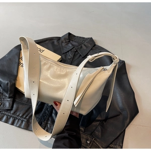 Detail of creamy white faux leather shoulder bag with wide grommet strap and metal zipper