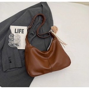 Detail of dark brown tote bag with wide shoulder strap and cute plush bear charm decoration