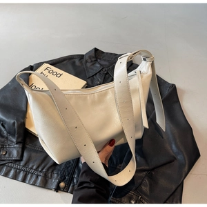 Detailed view of white faux leather dumpling bag with textured pleats on a black leather jacket