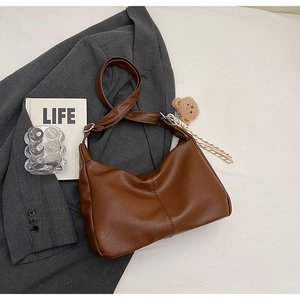 Detail of dark brown PU leather hobo bag featuring a cute plush bear charm and wide strap