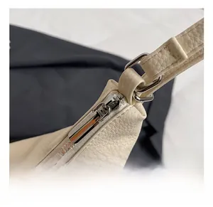 Macro shot of silver metal zippers and hardware hooks on a beige pebbled leather bag