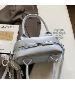 Detail of light blue leather boston bag with smooth hardware zipper and lace charm