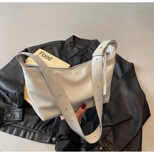 Top view of cream hobo shoulder bag with adjustable wide strap on black leather background