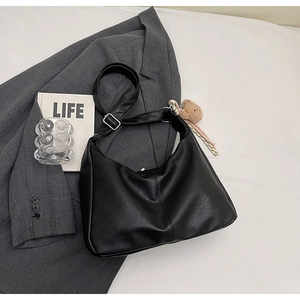 Close-up of black PU half-moon shoulder bag with plush bear charm and silver buckle