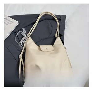 Close-up of beige lychee grain leather tote bag with lace and pearl charm detail