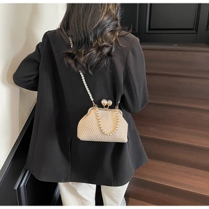 Detailed back view of a woven cream crossbody bag with pearl handle on a black blazer
