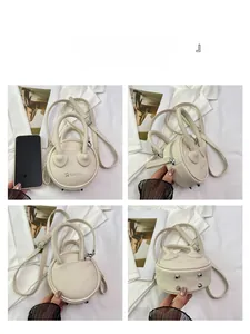 Detail view of mini round crossbody bag in cream white PU leather with lychee texture