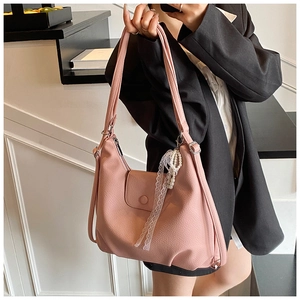 Detalle de bolso rosa con textura de cuero y elegante colgante de encaje y perlas