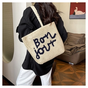 Dettaglio della borsa tote beige tessuta a mano con ricamo Bonjour nero per le vacanze