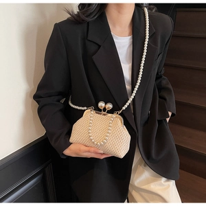 Detail of beige straw clutch bag featuring pearl strap and double pearl kiss-lock closure