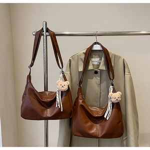 Detail of dark brown leather hobo bags in two sizes with bear charms and striped ribbons