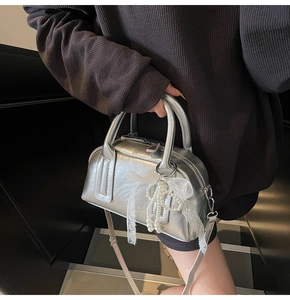 Detail of silver pillow bag with metallic texture and lace pearl bow accessory