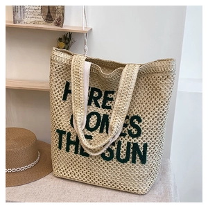 Detailed texture of beige woven beach tote with Here Comes The Sun green embroidery