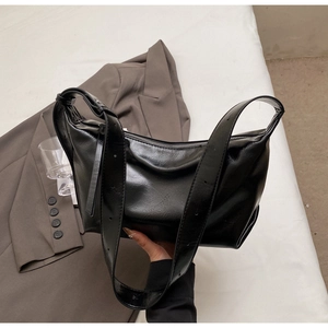 Close-up of black glossy leather hobo bag with pleated texture and adjustable strap