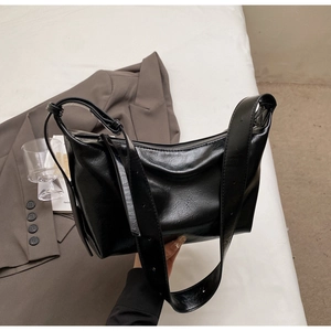 Close-up of black oil-wax leather hobo bag with silver zipper and wide strap detail