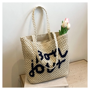 Dettaglio del ricamo Bon Jour su borsa tote in paglia intrecciata a mano color beige