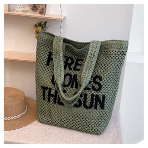 Close-up of woven straw tote bag featuring bold black Here Comes The Sun embroidery