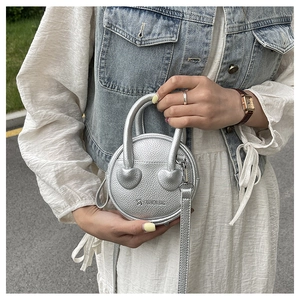 Gros plan du mini sac rond argenté avec détail en cœur et texte de mode gaufré