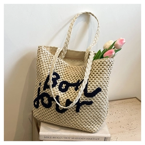 Dettaglio della borsa tote in paglia con ricamo Bonjour blu e decorazione floreale