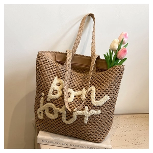 Dettaglio della borsa tote in paglia intrecciata a mano con scritta Bonjour e tulipani