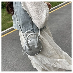 Street style shot of silver litchi grain mini bag with heart hardware and shoulder strap
