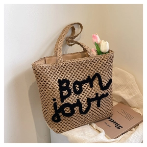 Dettaglio della borsa tote in paglia intrecciata a mano con ricamo Bon jour nero